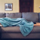 college-student-with-blanket-over-their-head-asleep-on-the-couch